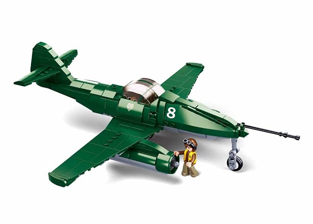 Toy model of a green airplane with a small figure next to it on a white background
