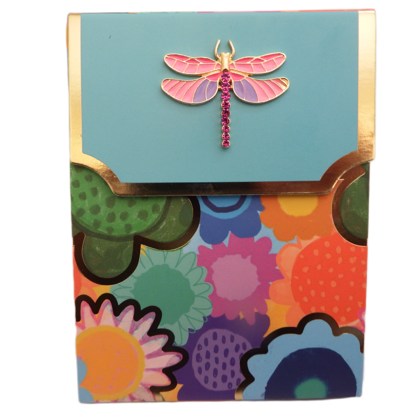 Colorful floral-patterned box with a pink dragonfly brooch on a light blue background