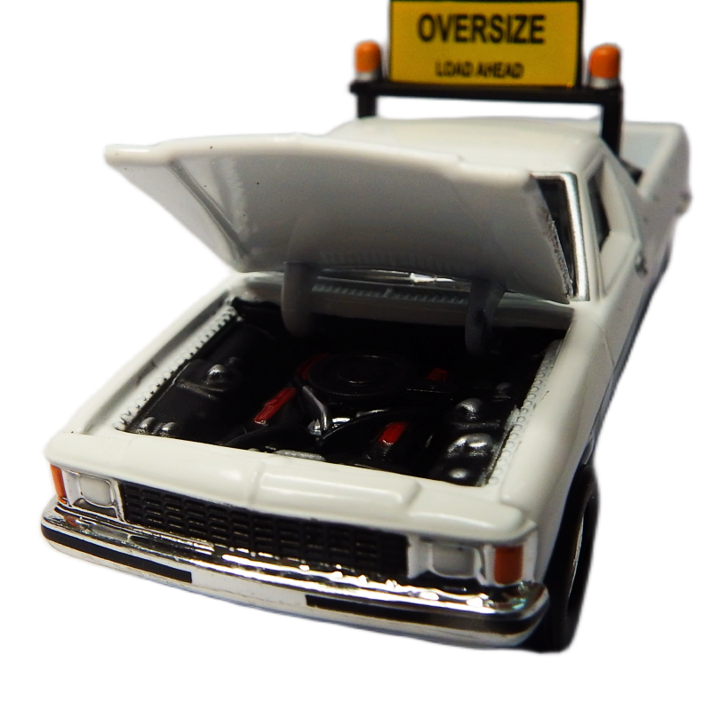 Model of a white truck with an open cargo area and 'Oversize Load Ahead' sign on a white background