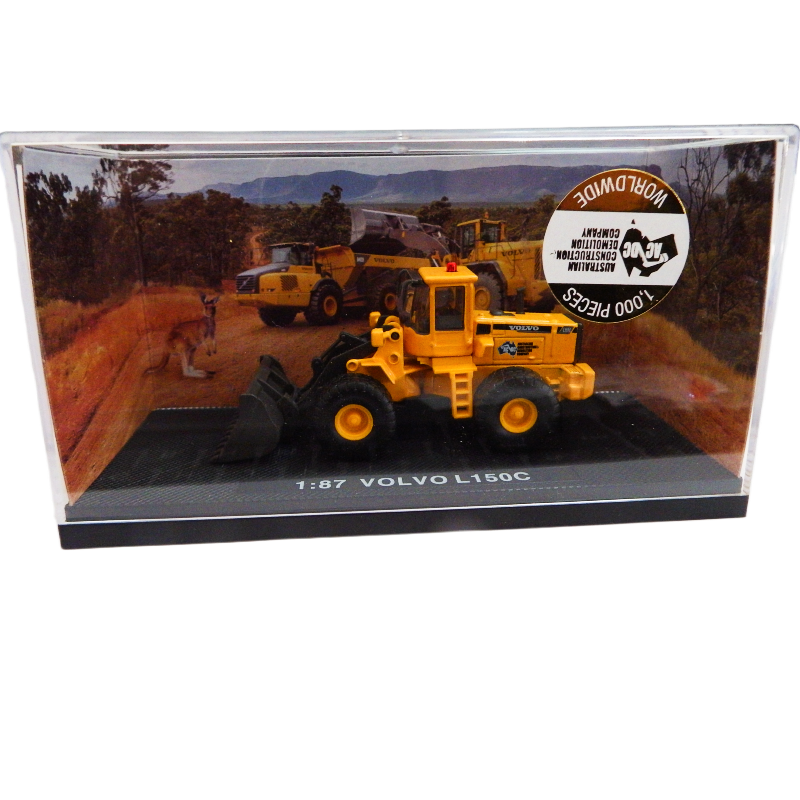 Model Volvo L150C construction vehicle in a display case with a scenic background.