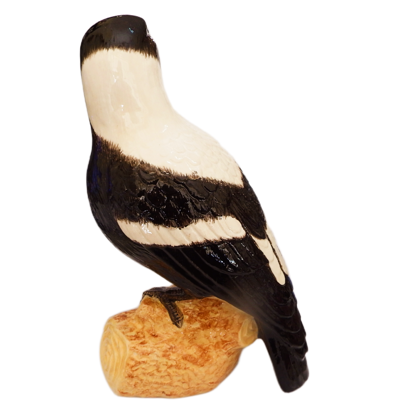 Australian Magpie bird ceramic figurine on a wooden perch against a white background