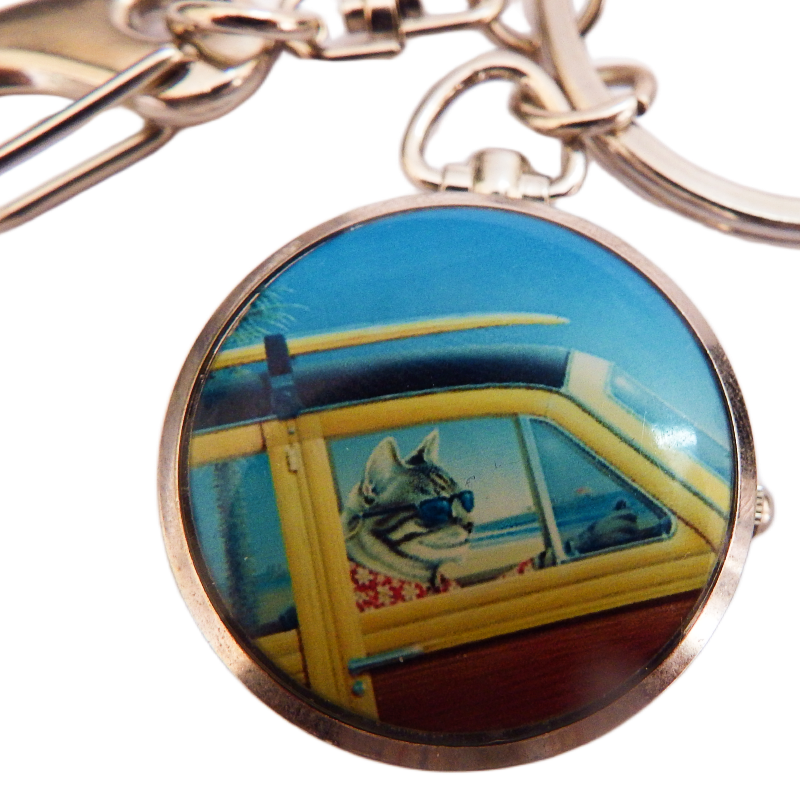 Keychain with a circular pendant clock featuring a cat in a car on a white background