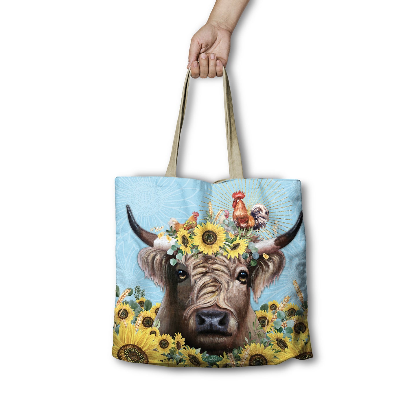 Tote bag with a cow and sunflower design held by a hand on a white background