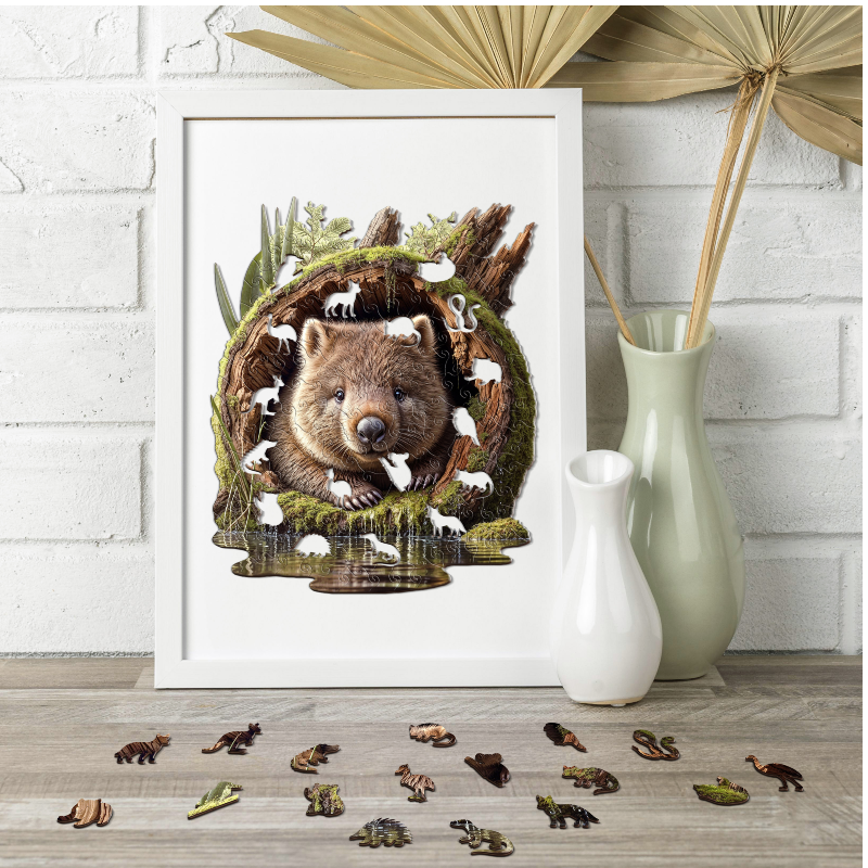 Framed artwork of a wombat in a forest scene, displayed on a table with decorative items.