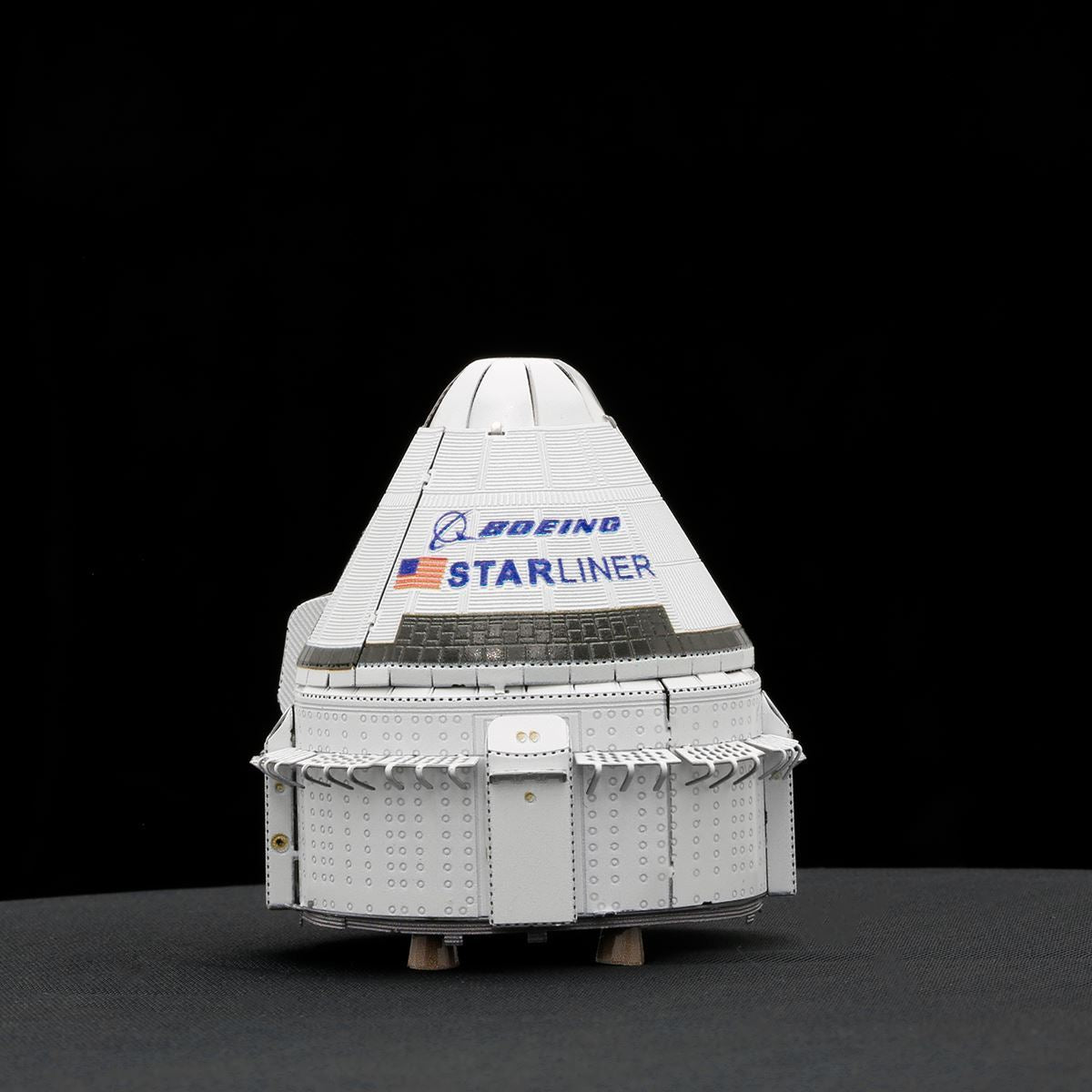 Model of Boeing Starliner spacecraft on a black background