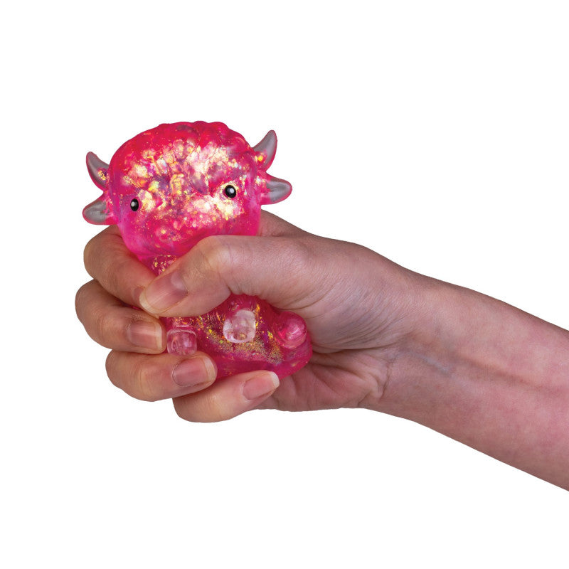 Hand holding a pink glowing stress ball with a highland cow design on a white background 