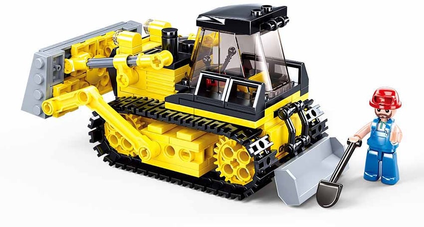 Toy bulldozer made of interlocking bricks with a small figure next to it on a white background