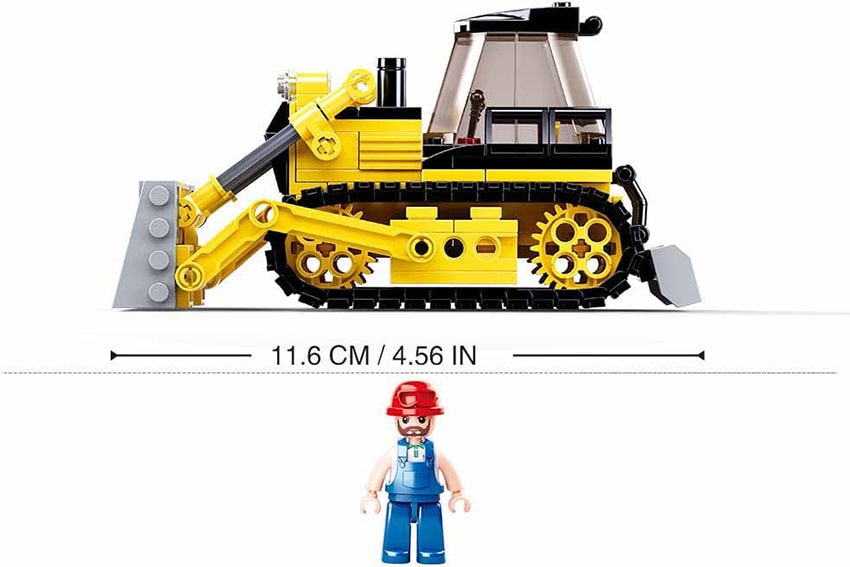 Toy bulldozer made of interlocking bricks with a figure for scale on a white background