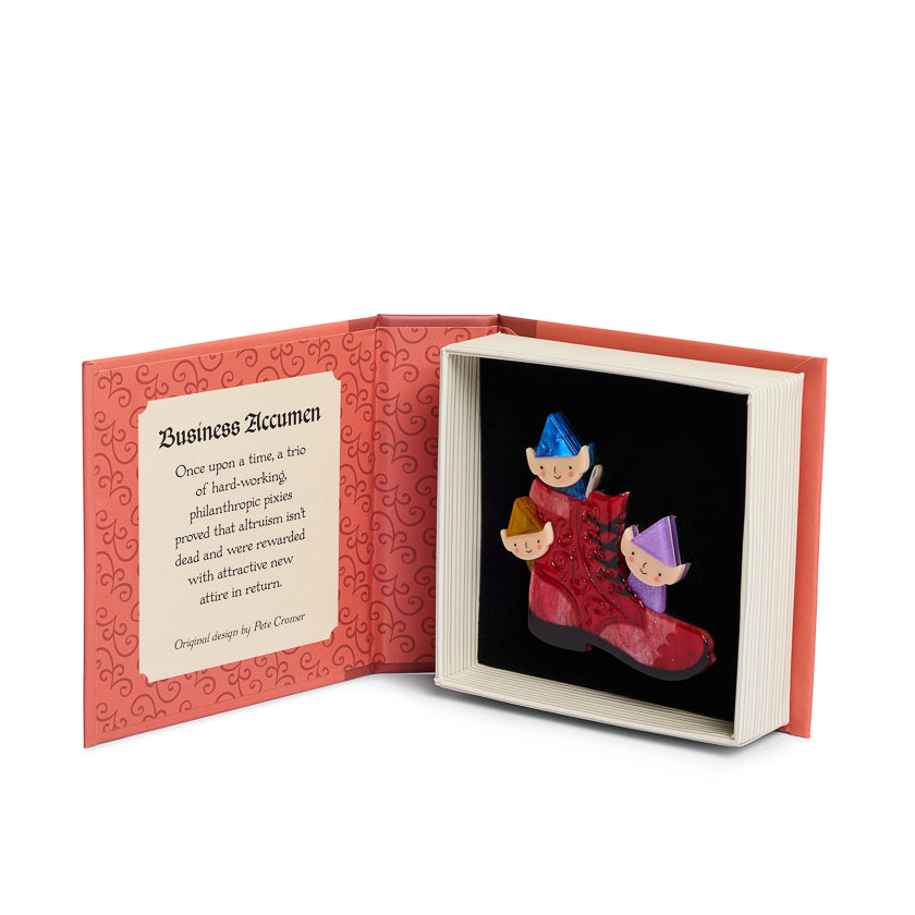 Open book with a red interior and a black cover featuring three colorful elf figures.