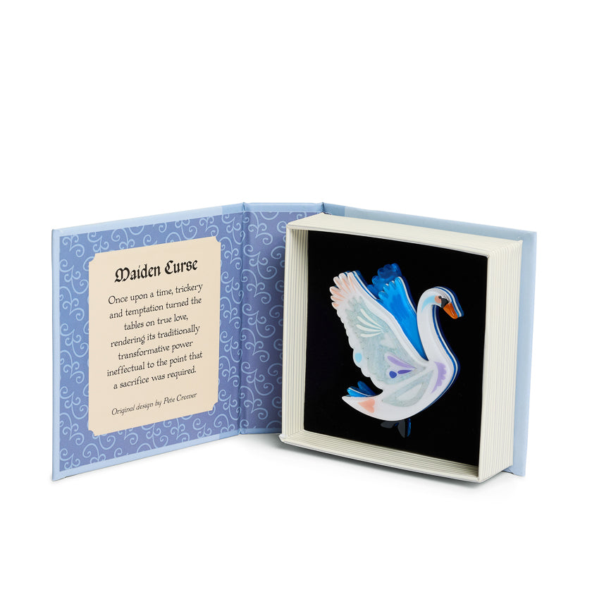 Open book box with a swan brooch and text on a white background
