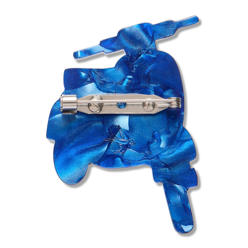 A blue vespa shaped brooch from the back with clasp into the shape of a scooter, with a silver metal pin clasp visible on the underside, set against a plain white background.