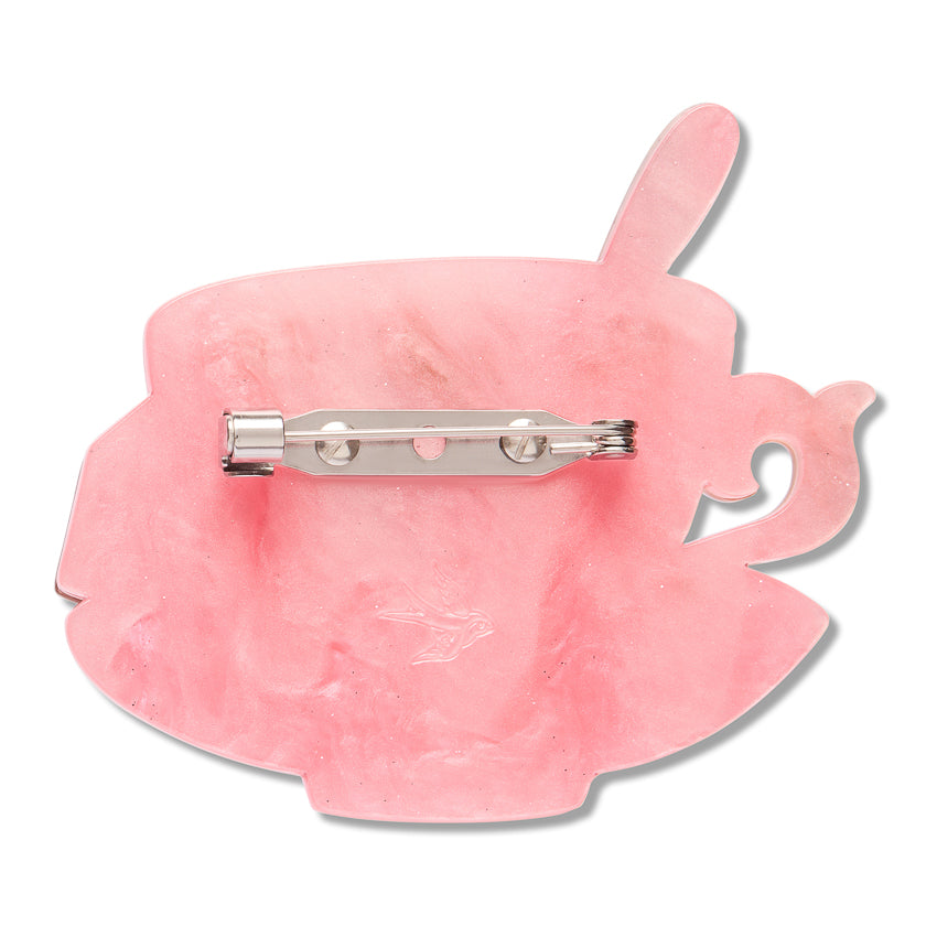 A pink teacup-shaped brooch with a silver metal pin clasp, shown from the back on a white background.