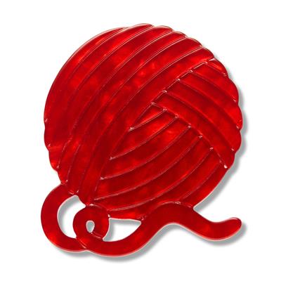 Red ball of wool brooch on a white background