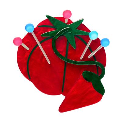 Red tomato-shaped object with green leaves and colorful sticks on a white background