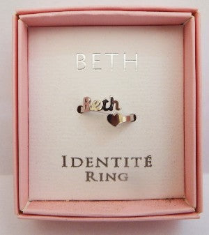 Ring with 'BETH' design in a pink box labeled 'IDENTITÓ RING'.