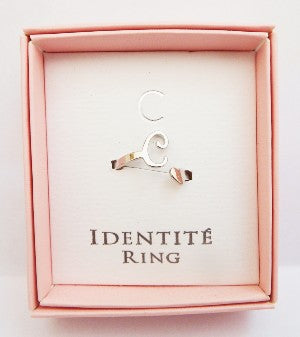 Silver ring in a pink box with ' IDENTITÓ RING' text on a light pink background