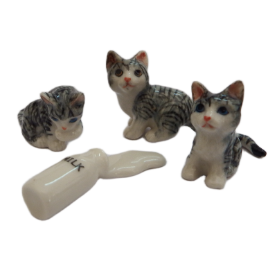 Three cat figurines and a white  bottle of spilt milk object with milk on a white background