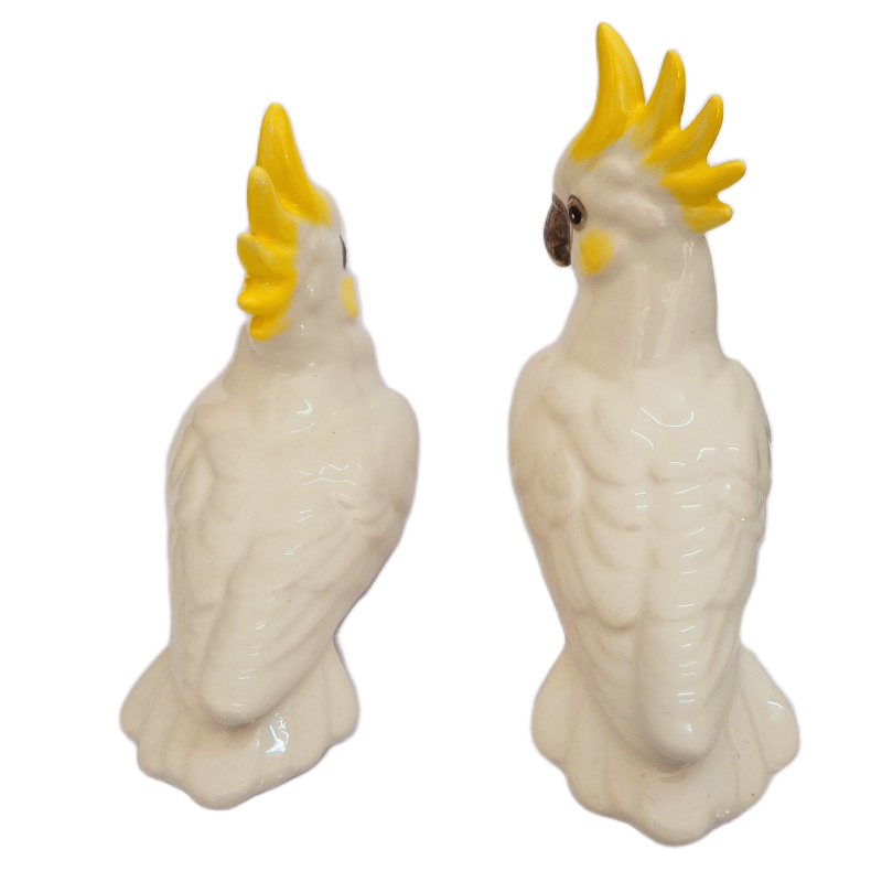 Two ceramic cockatoo figurines with yellow crests on a white background