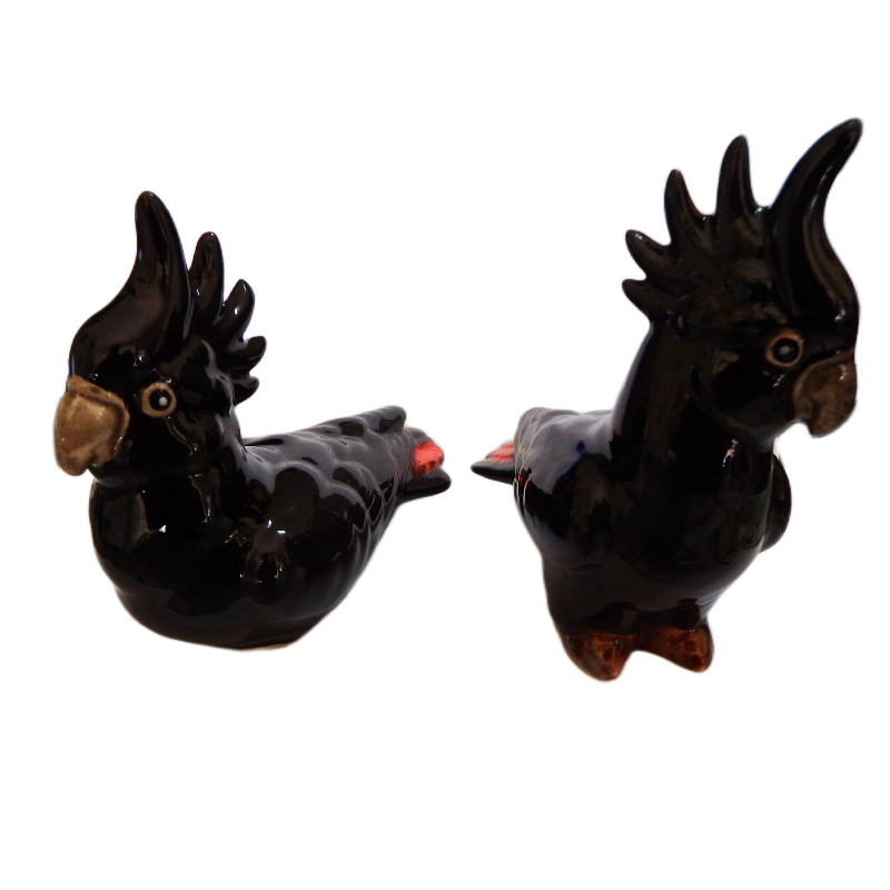 Two black red tail ceramic cockatoo figurines on a white background