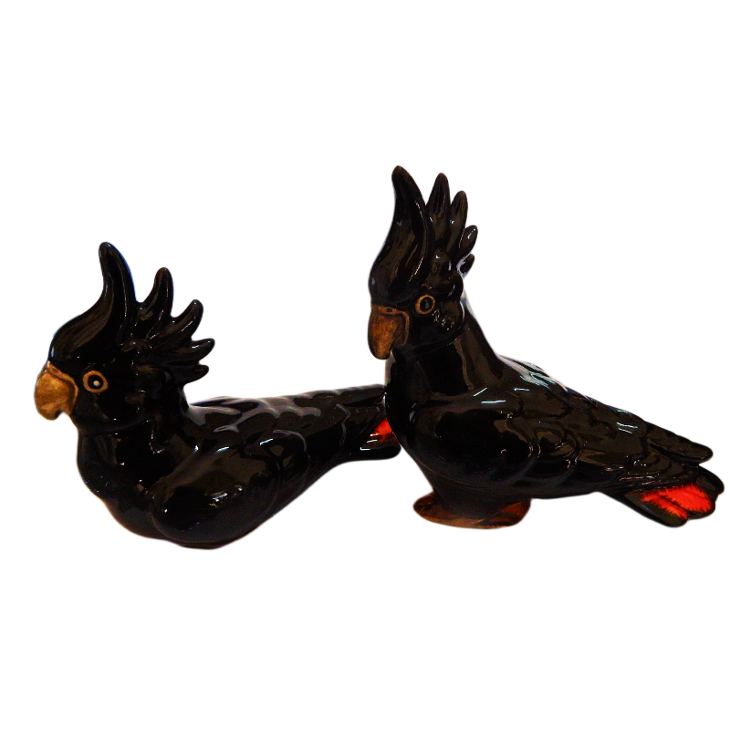 Two black cockatoo figurines on a white background