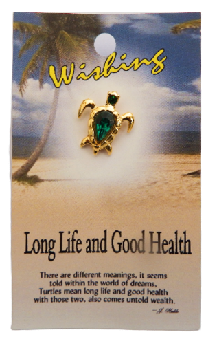 Tortoiseshell pendant with green gemstone on a card with beach scenery and text.