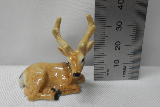 Small deer figurine next to a ruler on a white background