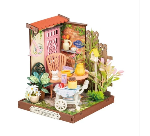 Miniature garden scene with a small house, table, Tea Setting and plants on a white background 