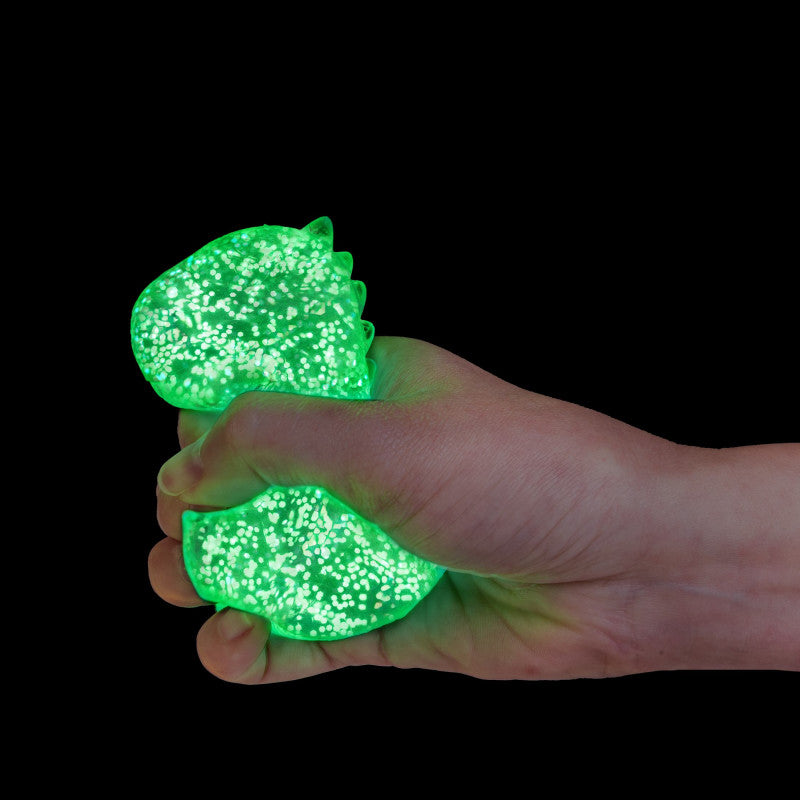 Hand holding a green glittery stress ball against a black background