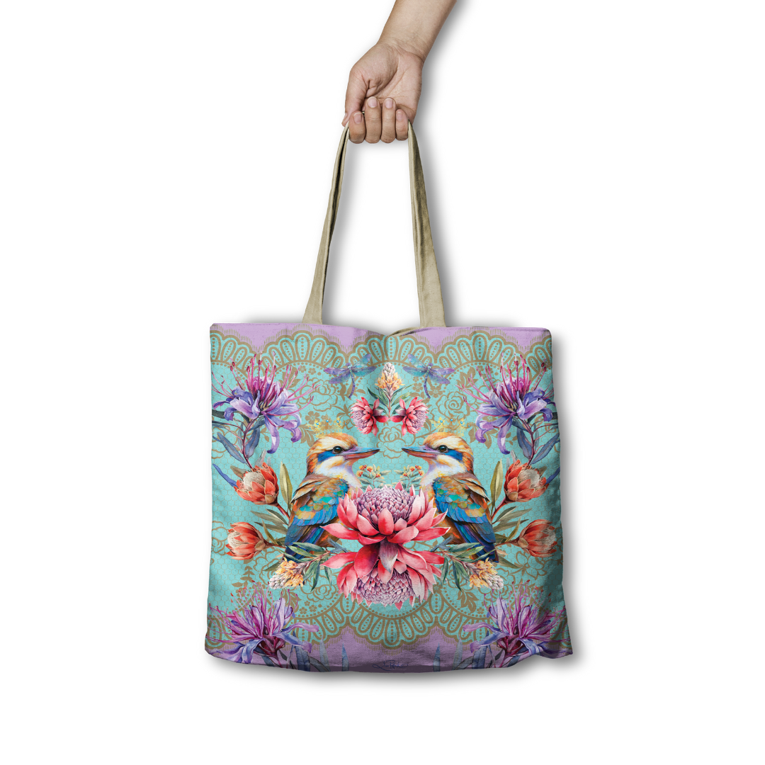 Tote bag with floral and bird design held by a hand on a white background