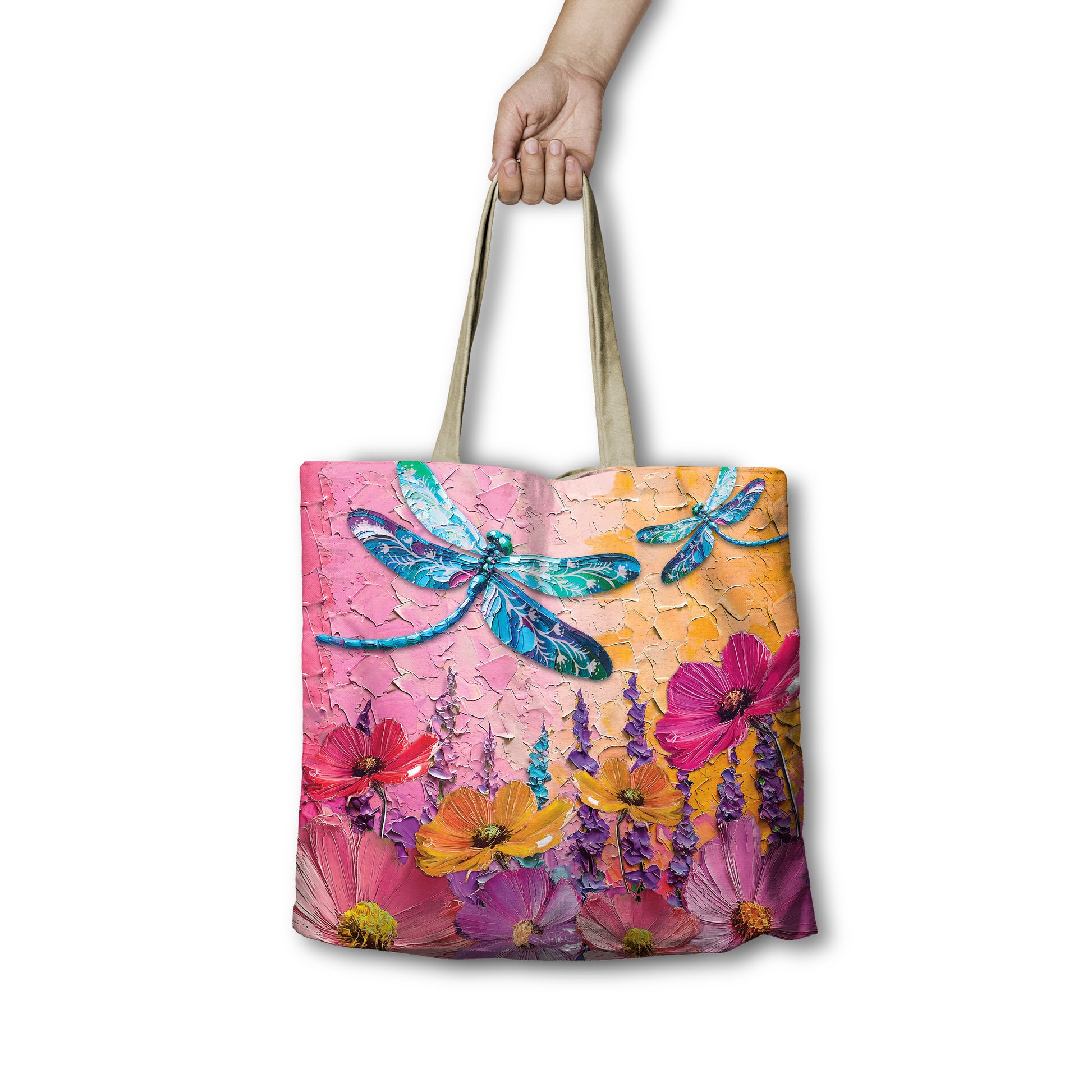Tote bag with floral and dragonfly design held by a hand on a white background