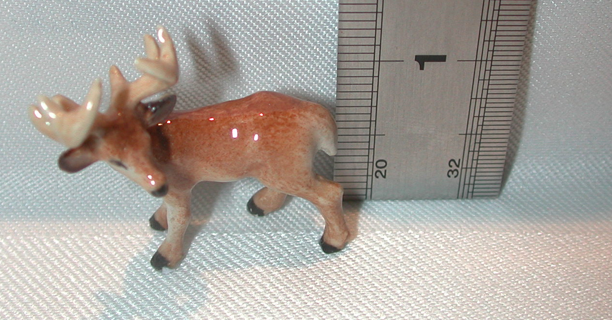Small figurine of a deer next to a ruler on a textured surface