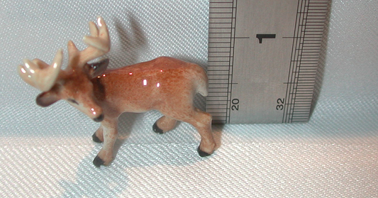 Small figurine of a deer next to a ruler on a textured surface