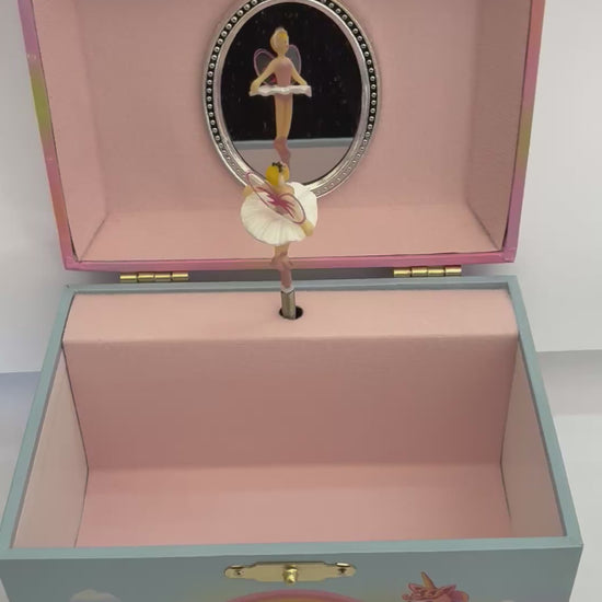 movie  of open fairy  jewelry box with pink lining with fairy figurine spinning around to the tune of swan lake in front of a mirror 