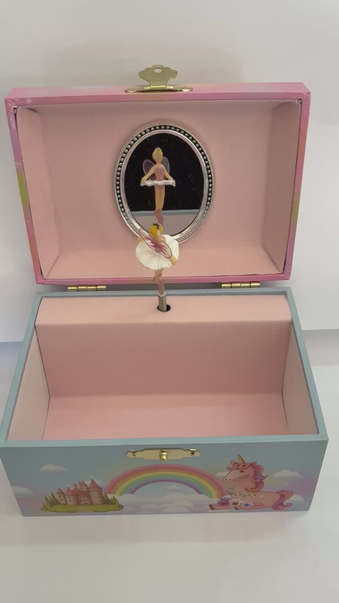 movie  of open fairy  jewelry box with pink lining with fairy figurine spinning around to the tune of swan lake in front of a mirror 