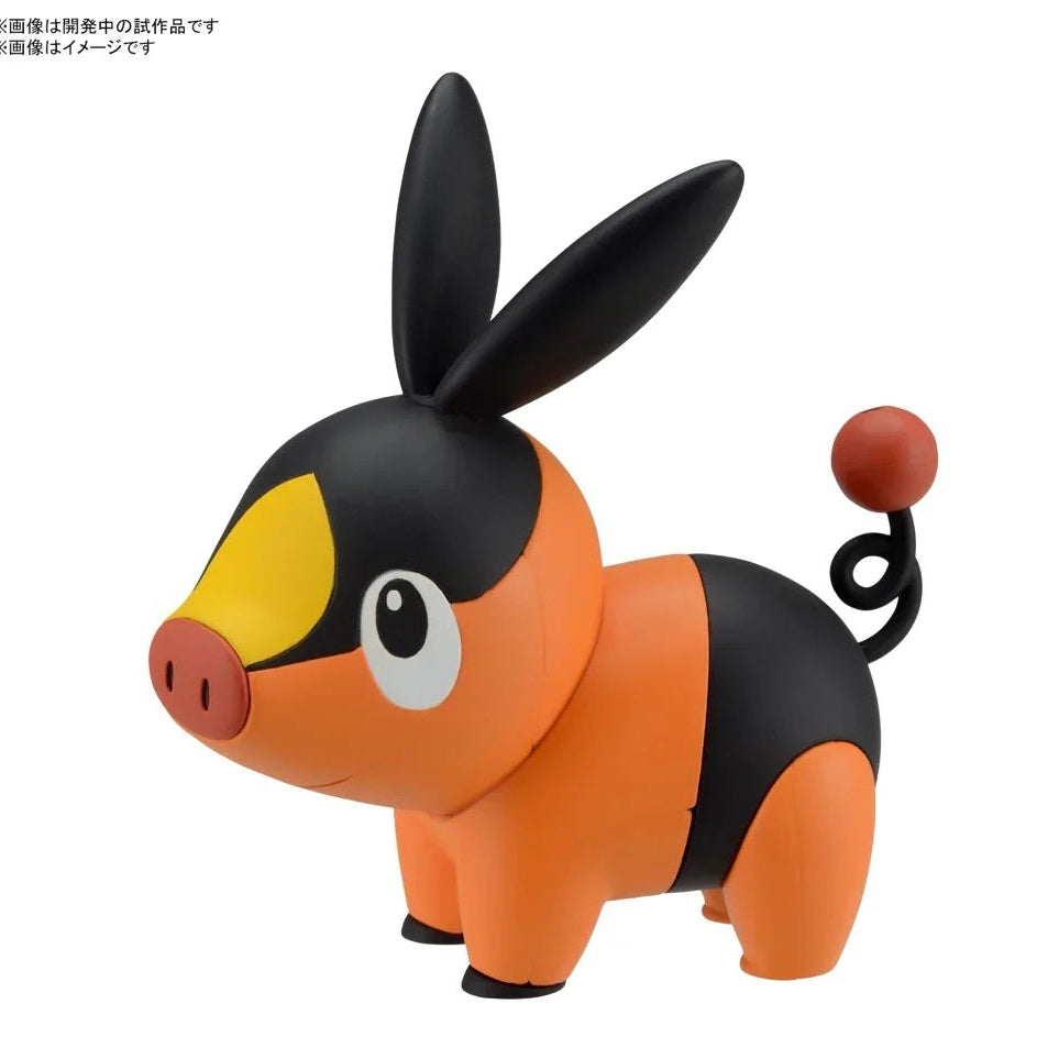 Toy figure of a black and orange creature with large ears on a white background