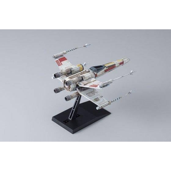 A detailed model of a Star Wars X-wing TIE fighter on a black display stand, photographed against a neutral gray studio background.