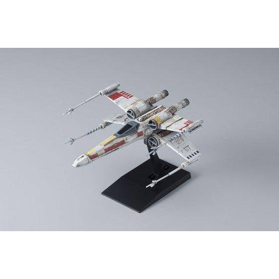 Model of a Star Wars X-wing fighter on a stand with a gray background