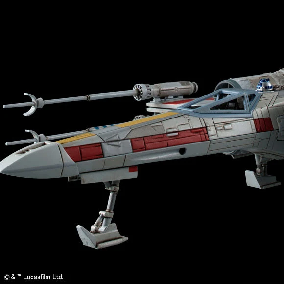 A detailed model of an X-wing Starfighter, shown from a side profile view against a solid black background. The model features a silver-gray fuselage with red and yellow accent panels, a blue canopy, and a small blue-and-white droid inside the cockpit.